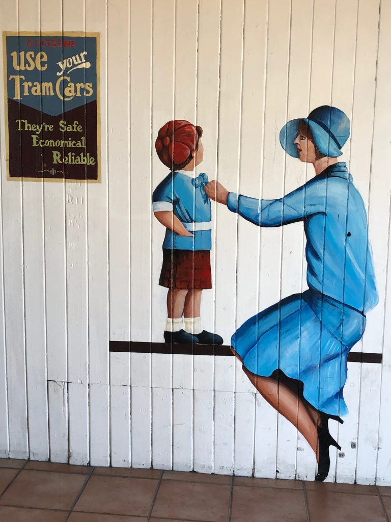 Street art in Napier, New Zealand, depictng a 1920s scene of a woman and child waiting for a tram.